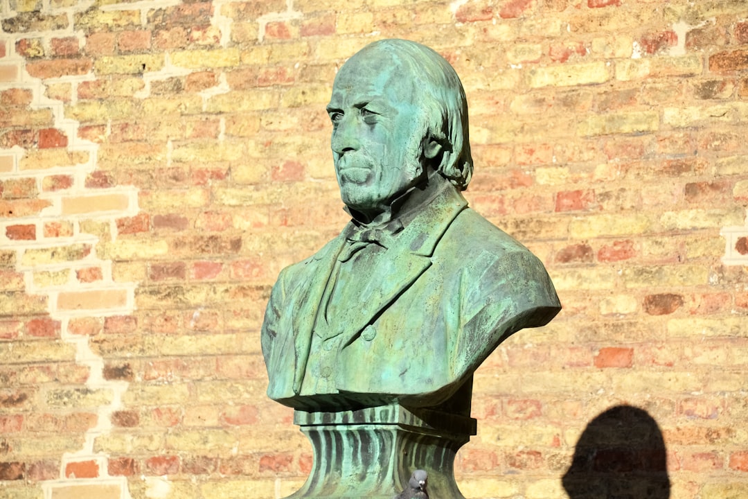 man statue near brown brick wall