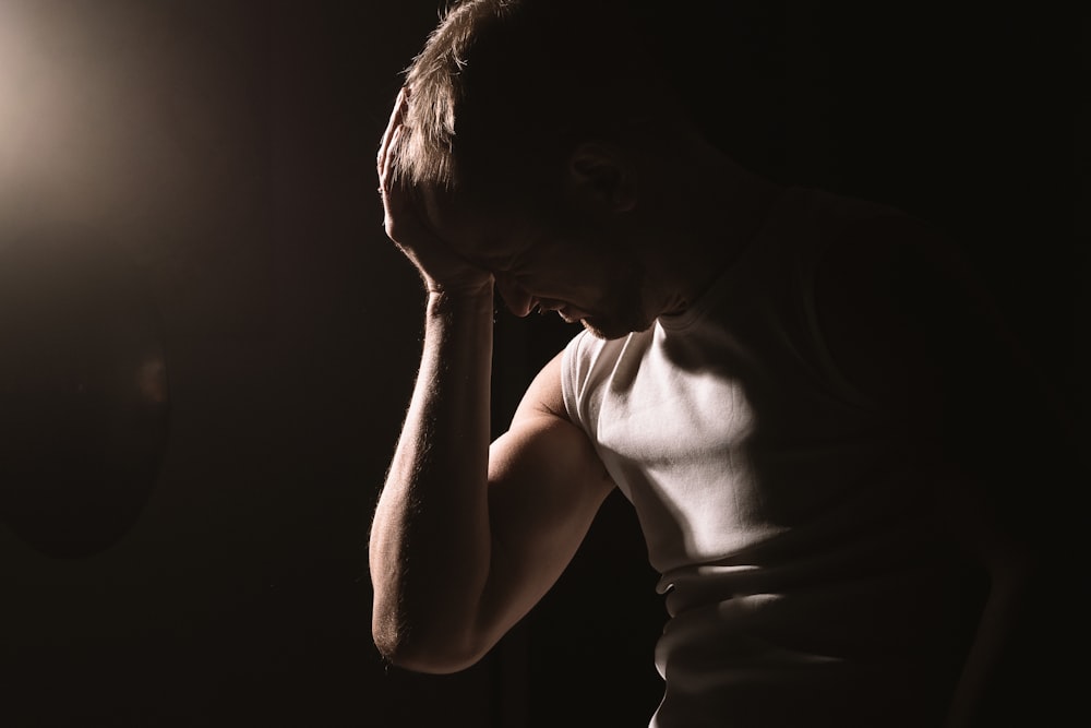 man in tank top holding his head