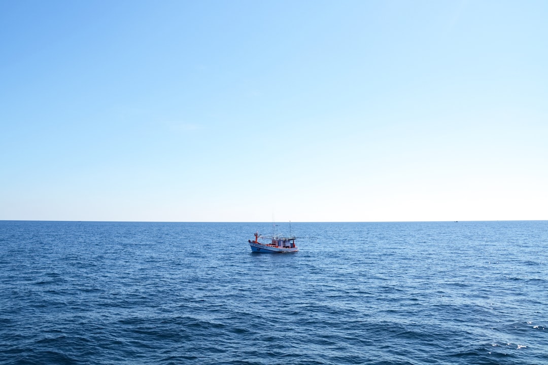 white and red boat on sea under blue sky during daytime