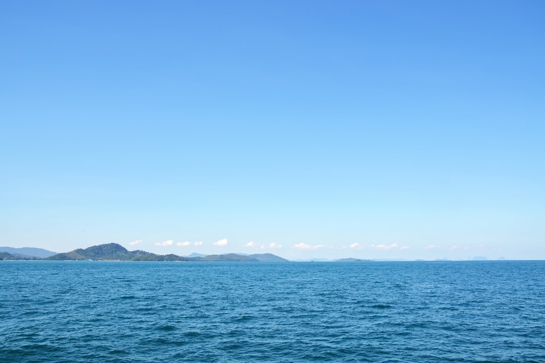 blue sea near mountain under blue sky during daytime