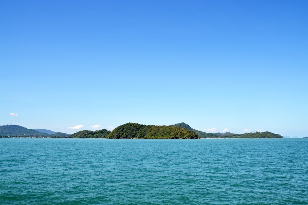 green and brown mountain beside body of water during daytime