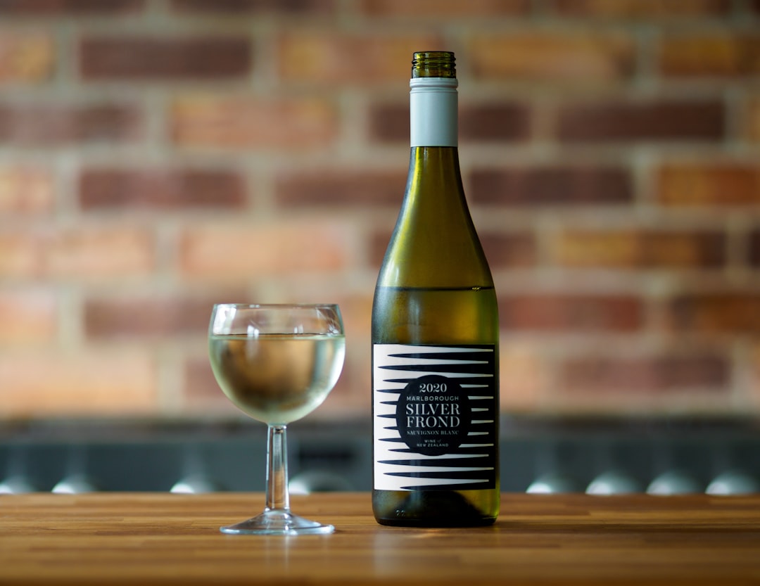 black and white labeled bottle beside clear wine glass on brown wooden table