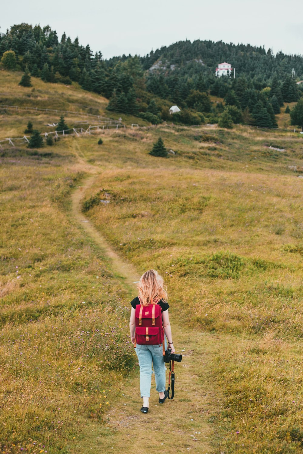 woman in red jacket walking on green grass field during daytime