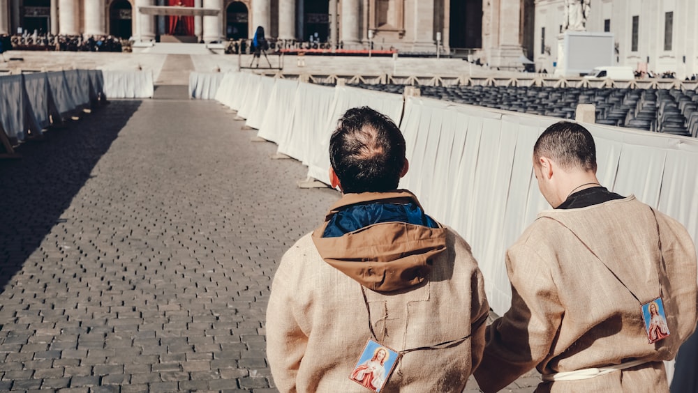 man in brown jacket walking on sidewalk during daytime