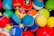 A collection of colorful Pokémon themed balls, each with distinct designs and logos. The balls are tightly packed together, showcasing a variety of vibrant colors and patterns.