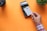 A hand is holding a white credit card near a point-of-sale terminal. The background is an orange surface, and there is a plant and a cup also present in the image.