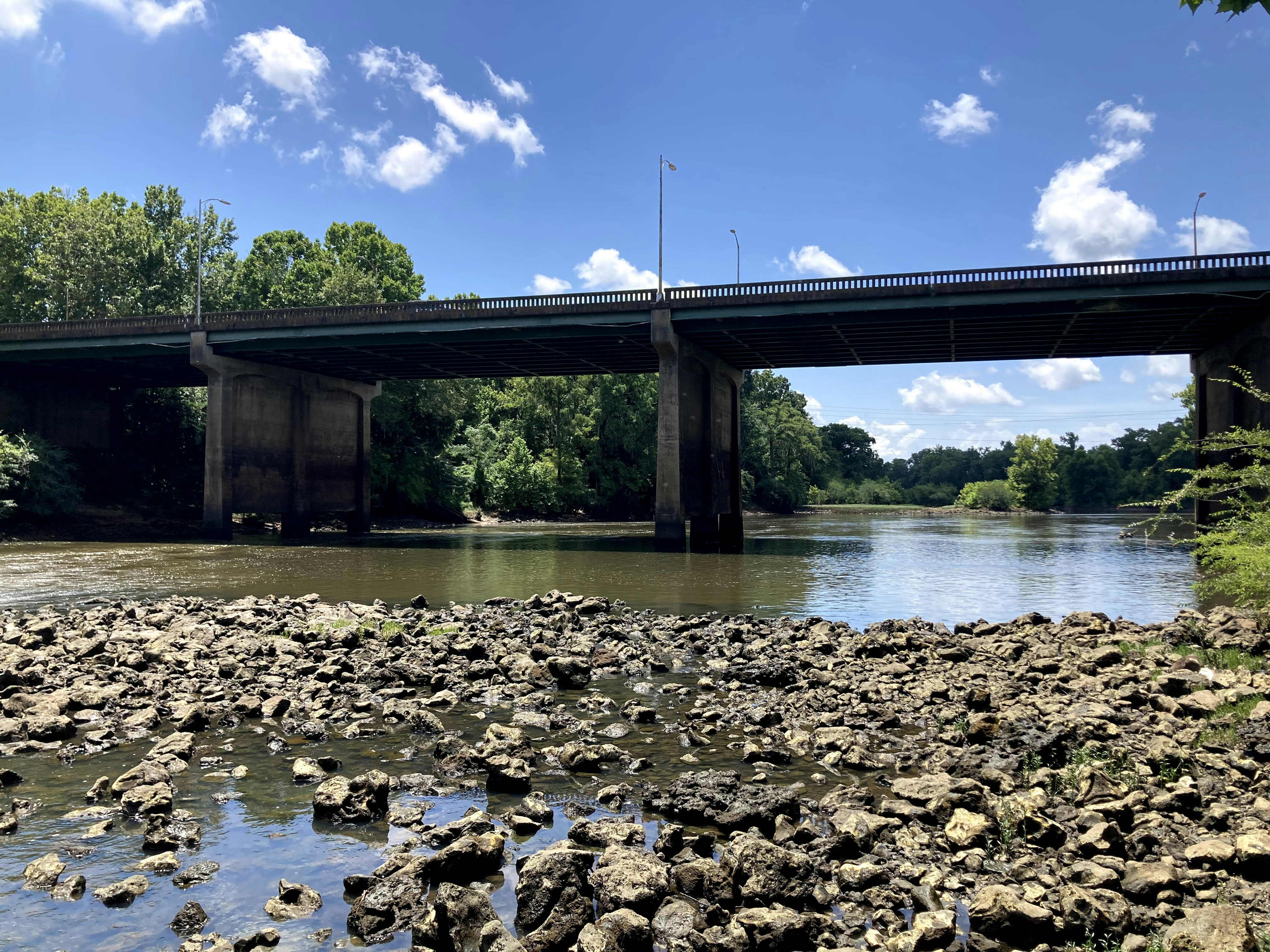 Concrete bridge over river, bright daylight, open rural landscape, infrastructure project