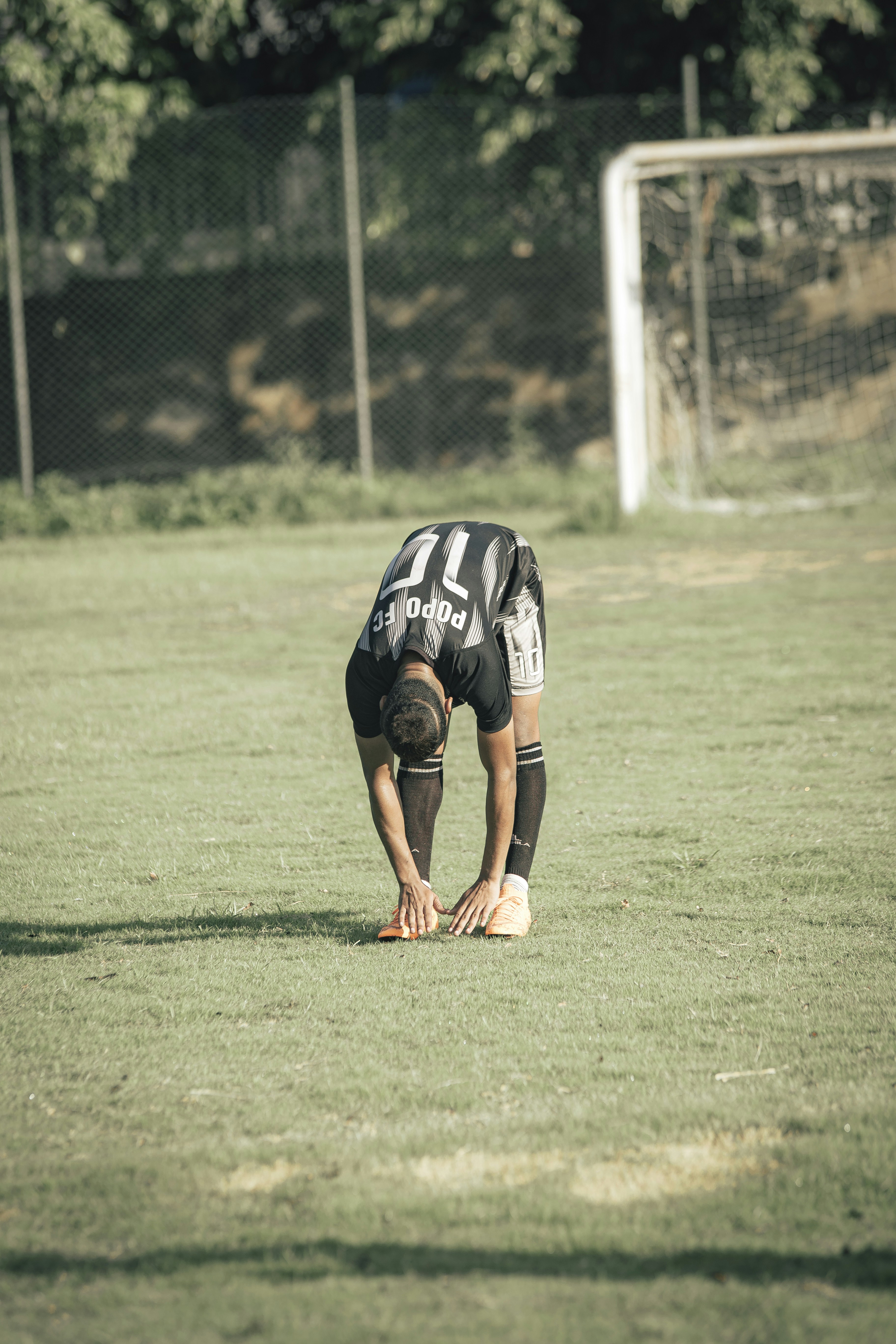 man in black and white jersey shirt and black shorts playing soccer during daytime