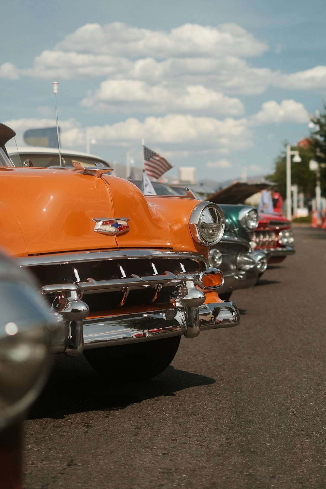 orange and silver vintage car on gray asphalt road during daytime