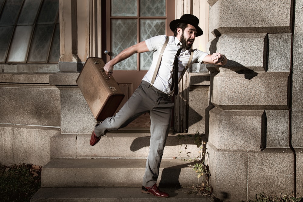 man in white dress shirt and gray pants sitting on gray concrete stairs