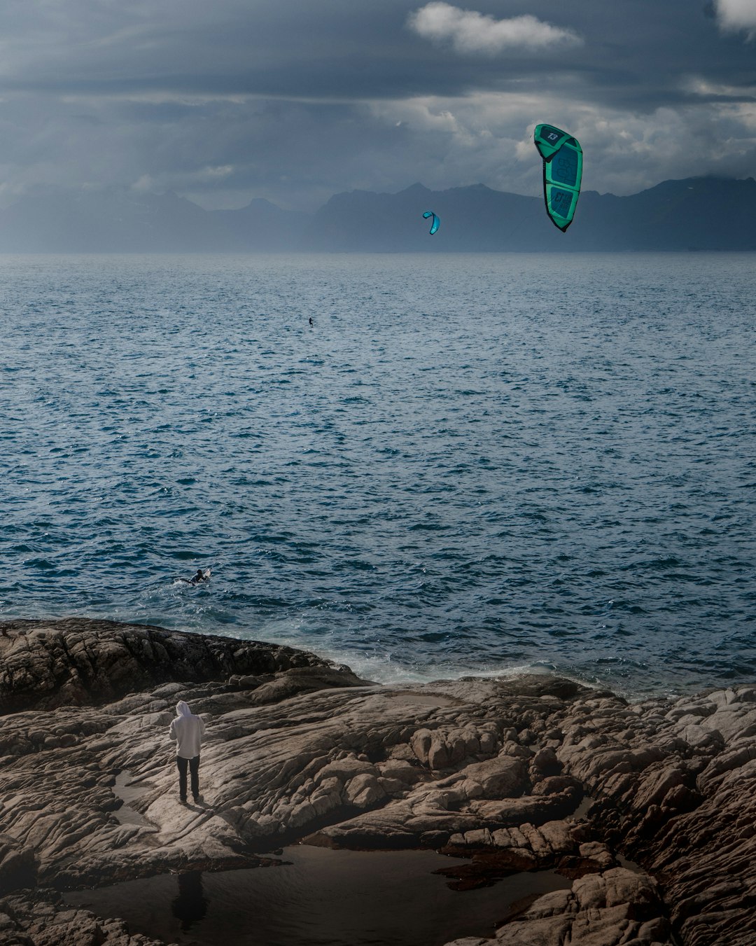 person holding blue and green kite surfing on sea during daytime