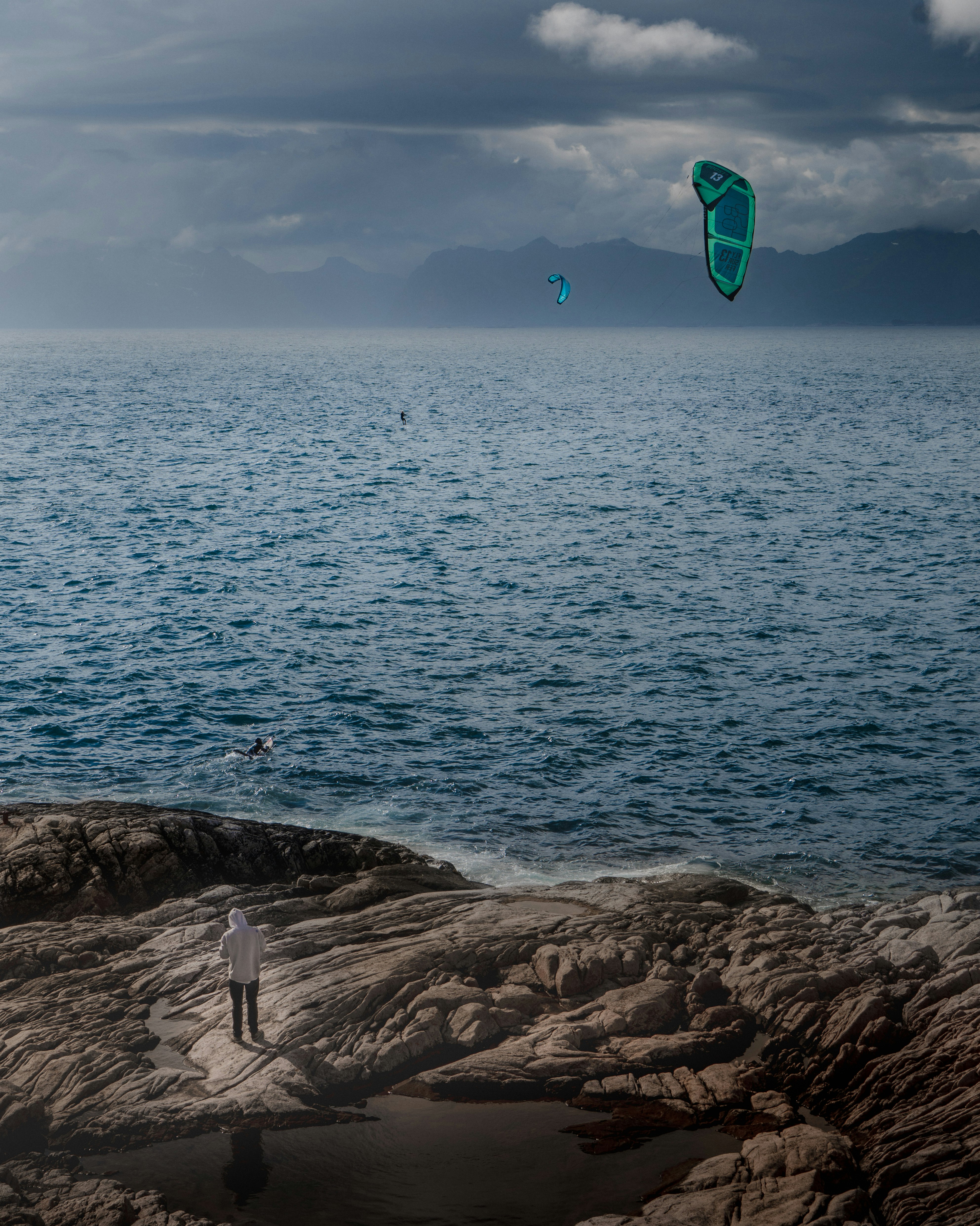 person holding blue and green kite surfing on sea during daytime