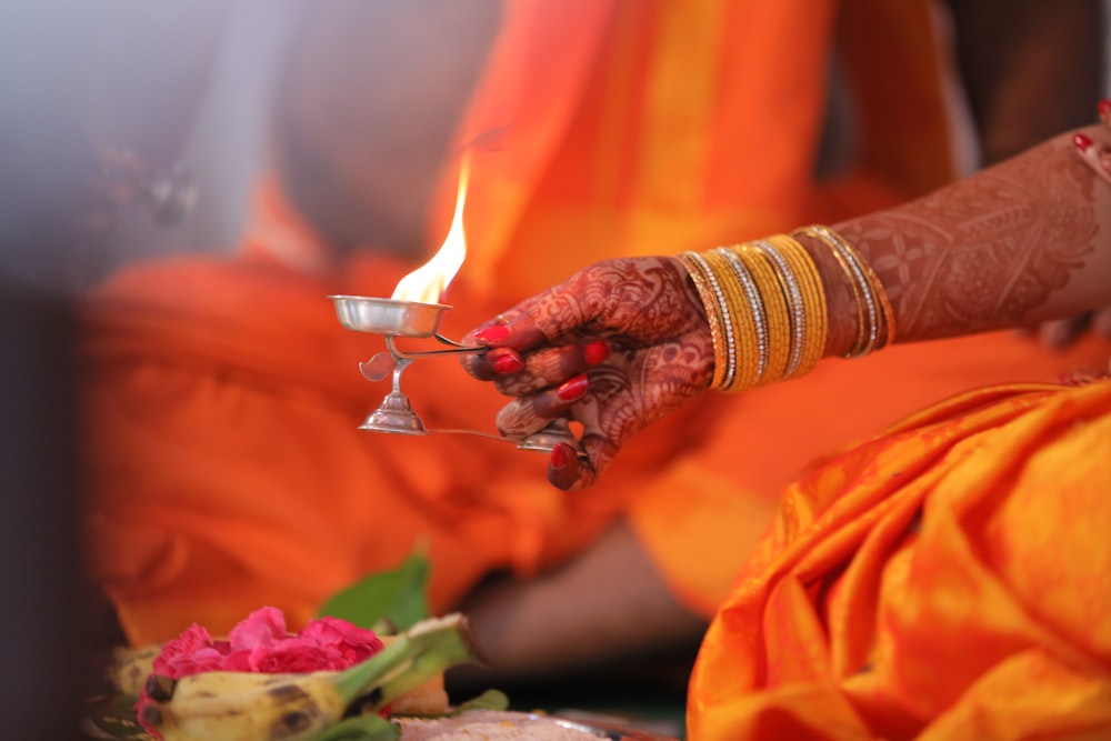 person in orange dress holding white candle