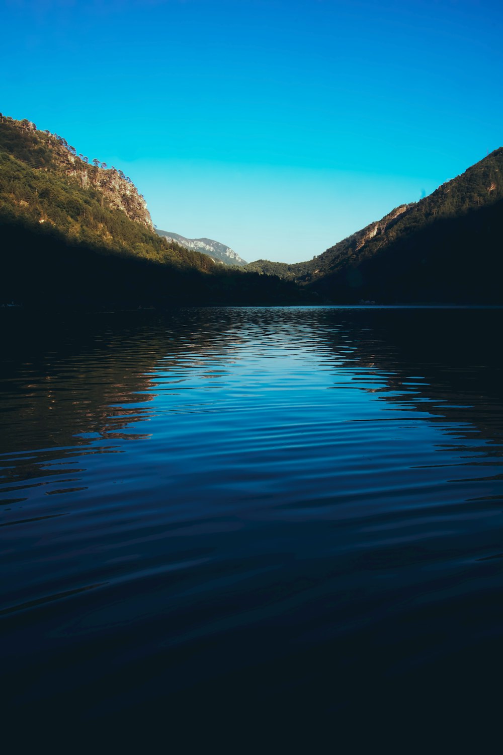 body of water near mountain during daytime