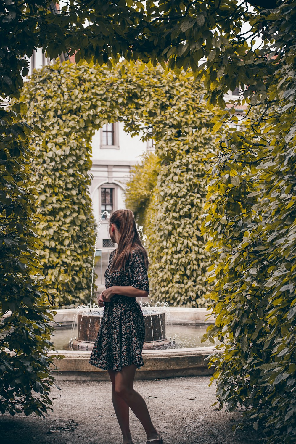 Donna in abito bianco e nero in piedi vicino alla pianta verde durante il giorno