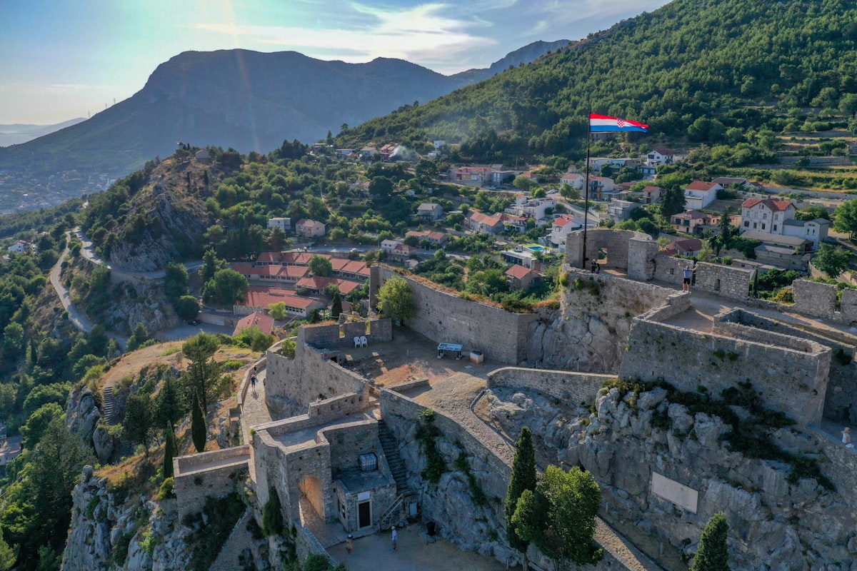 Split October — aerial view of Klis Fortress on its dramatic hilltop with the Mosor mountain range behind, a day trip from Split