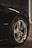 A close-up view of a car's chrome alloy wheel and tire, featuring a logo at the center. The wheel is shiny and well-maintained, with visible tire tread. A badge labeled 'HEMI' is visible on the car's dark paintwork, indicating a high-performance engine.