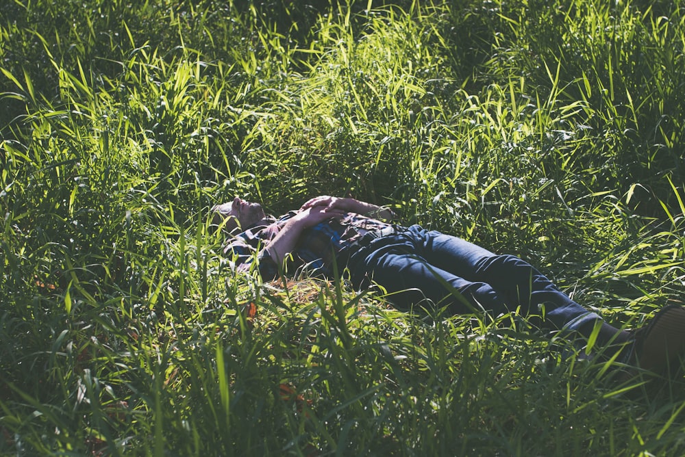 woman lying on green grass field during daytime
