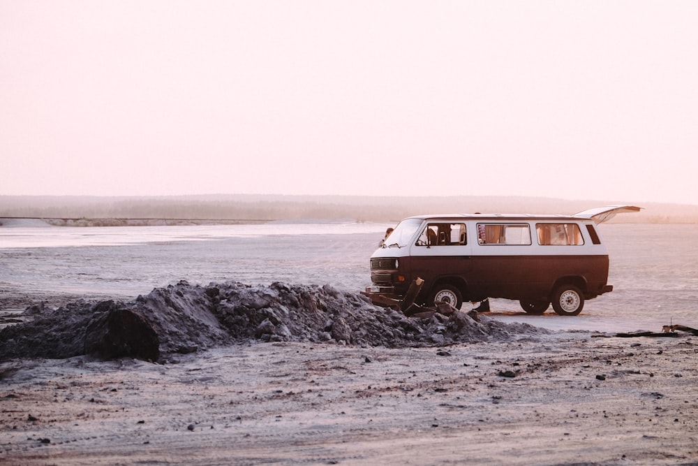 white and red van on brown sand near body of water during daytime