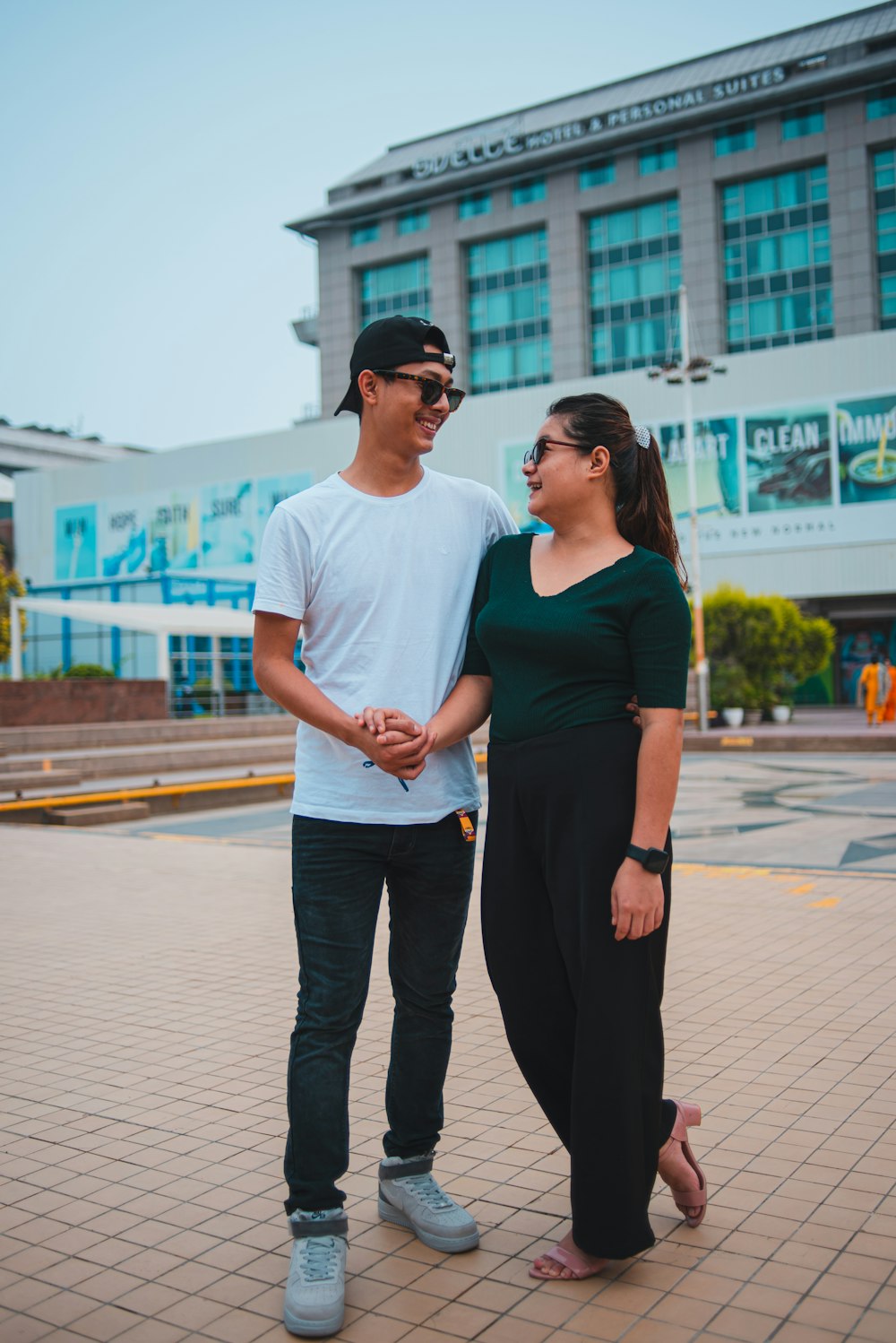 man in white crew neck t-shirt and black pants standing beside woman in black dress