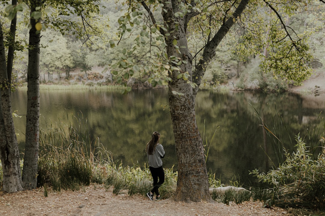 woman in black jacket and black pants standing near lake during daytime