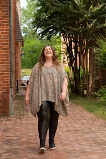 A woman walking confidently down a quiet street with gentle terracotta hues in the background.