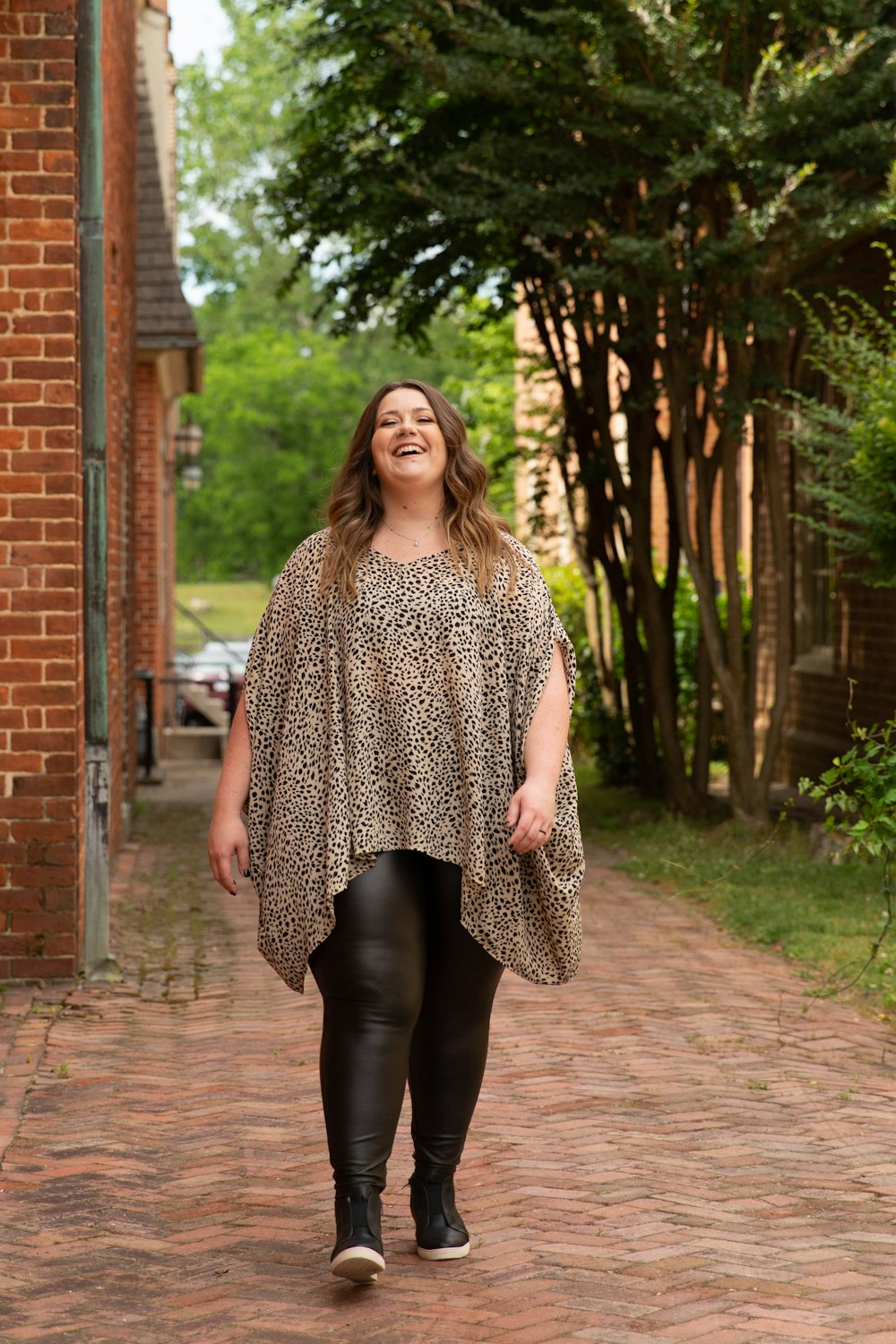 woman in black and white leopard print dress standing on brown brick pathway