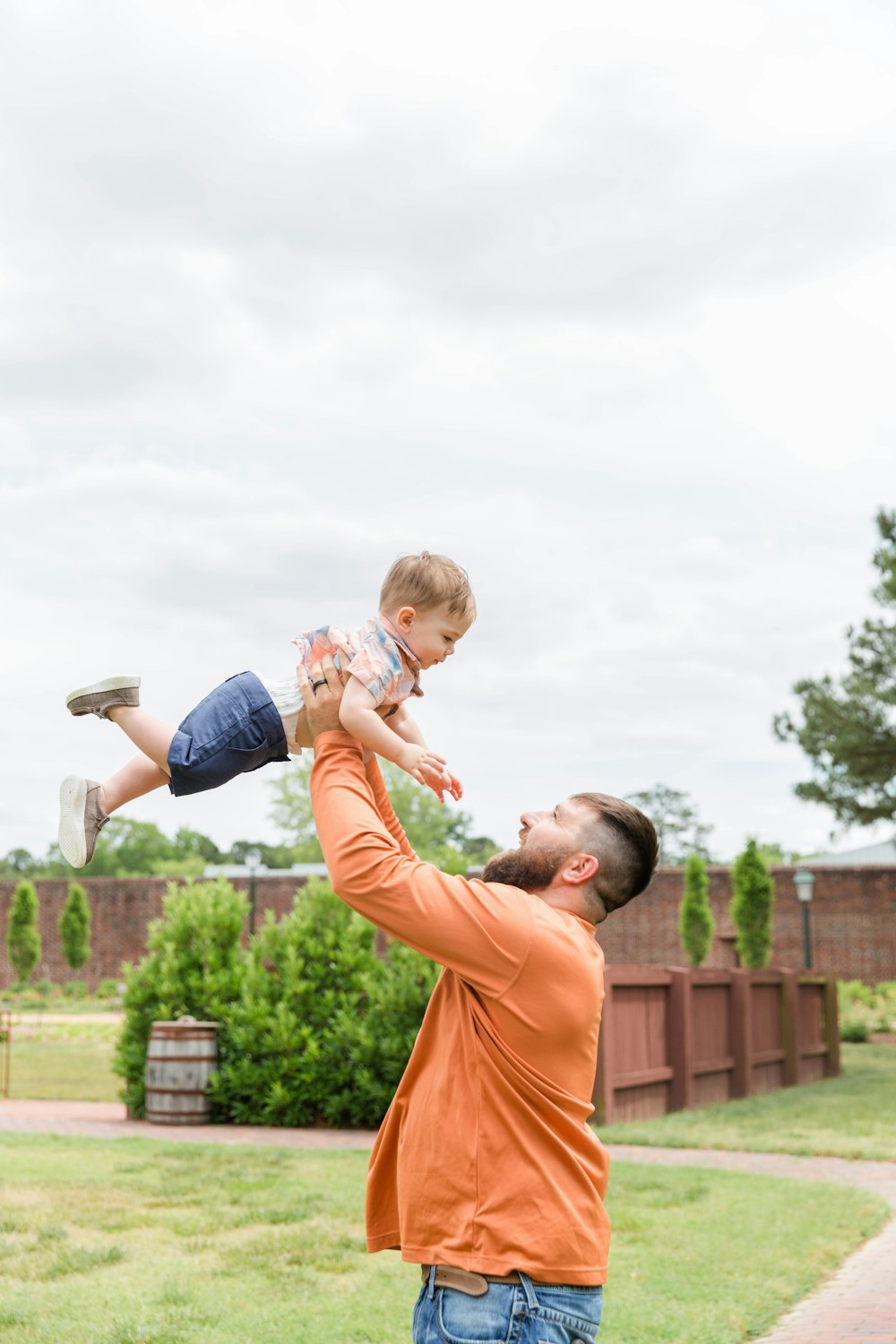 man in orange t-shirt carrying girl in blue denim shorts during daytime