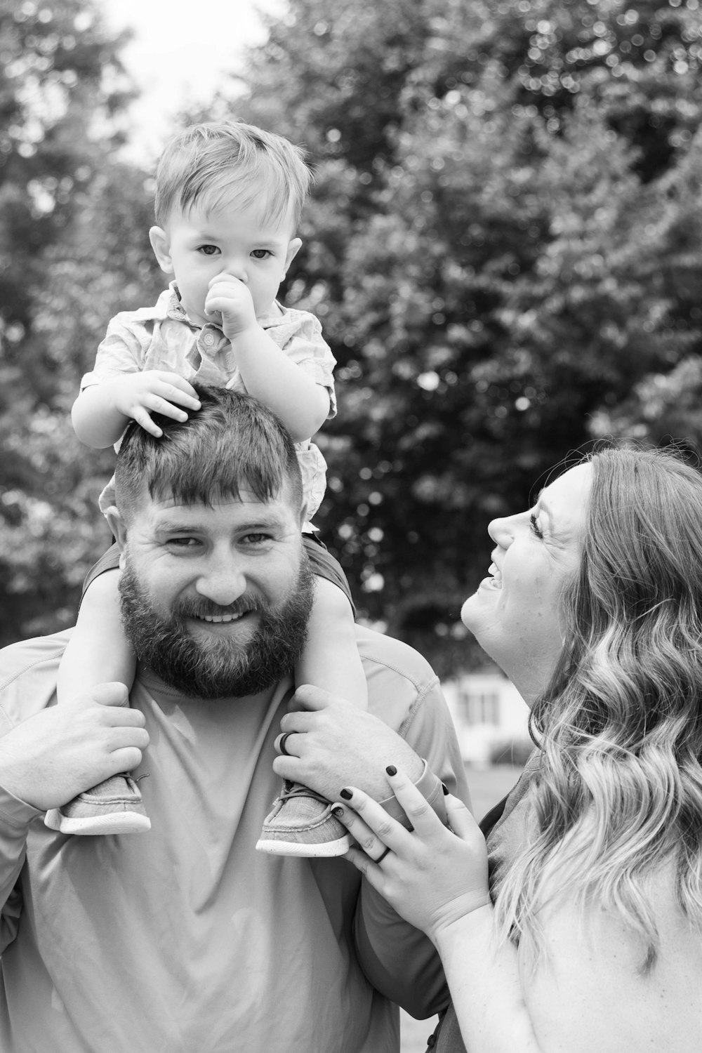 man in white dress shirt carrying baby in grayscale photography