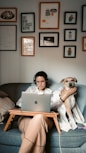 woman in white long sleeve shirt sitting on gray couch with macbook