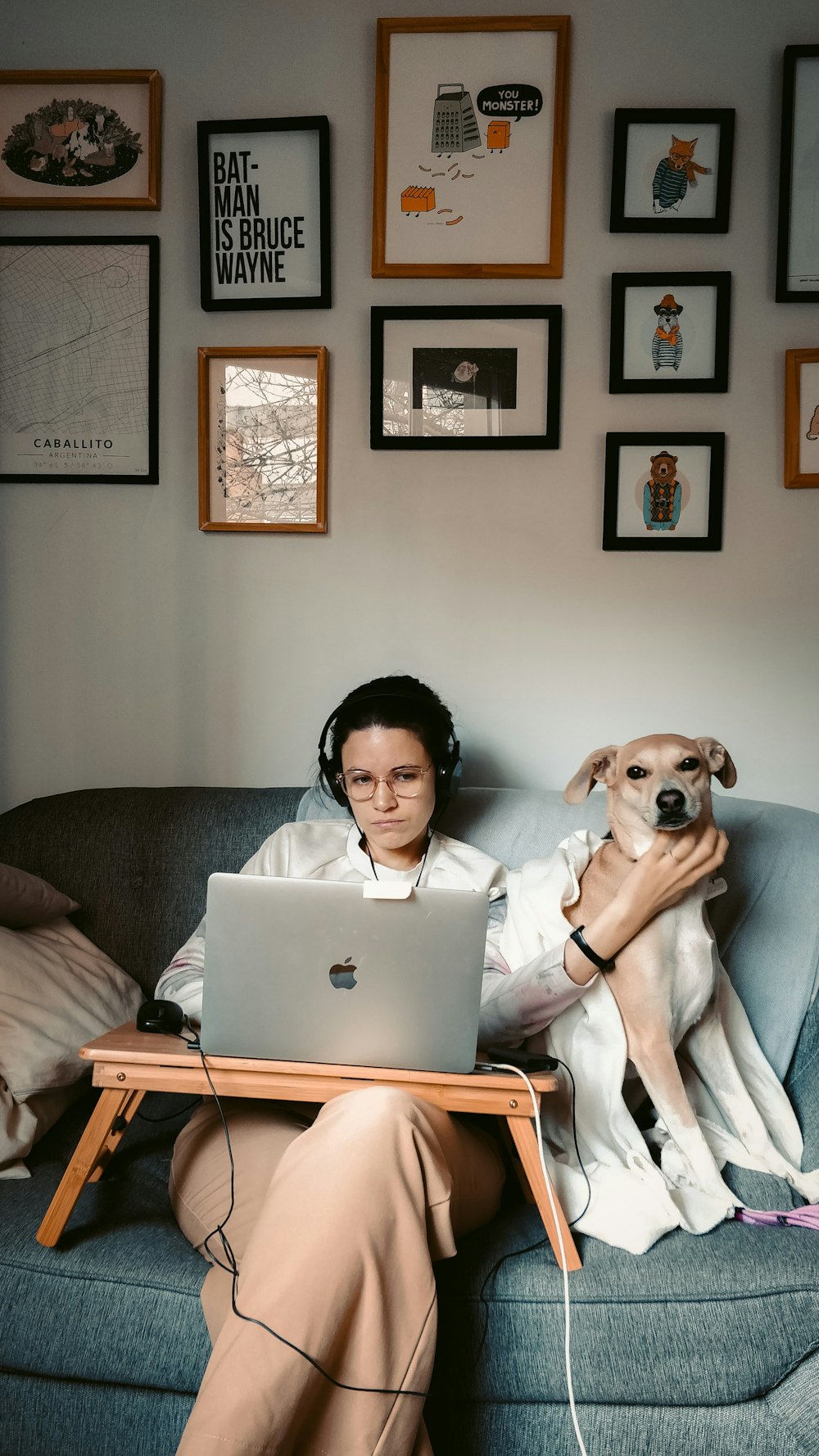 Frau im weißen Langarmhemd sitzt auf grauer Couch mit MacBook