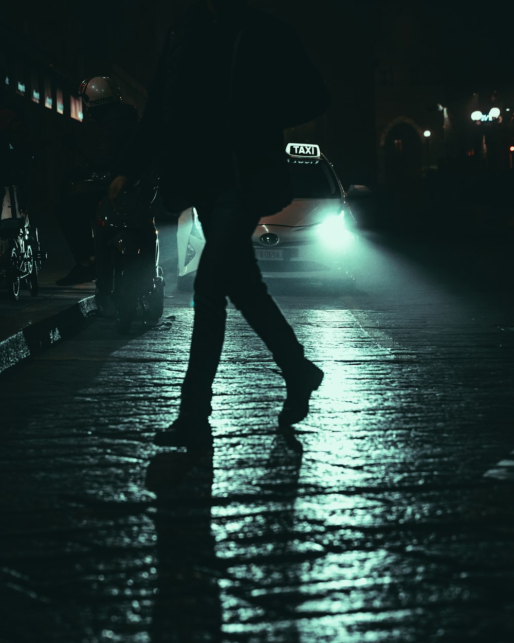 Mann in schwarzer Jacke geht nachts auf der Straße spazieren