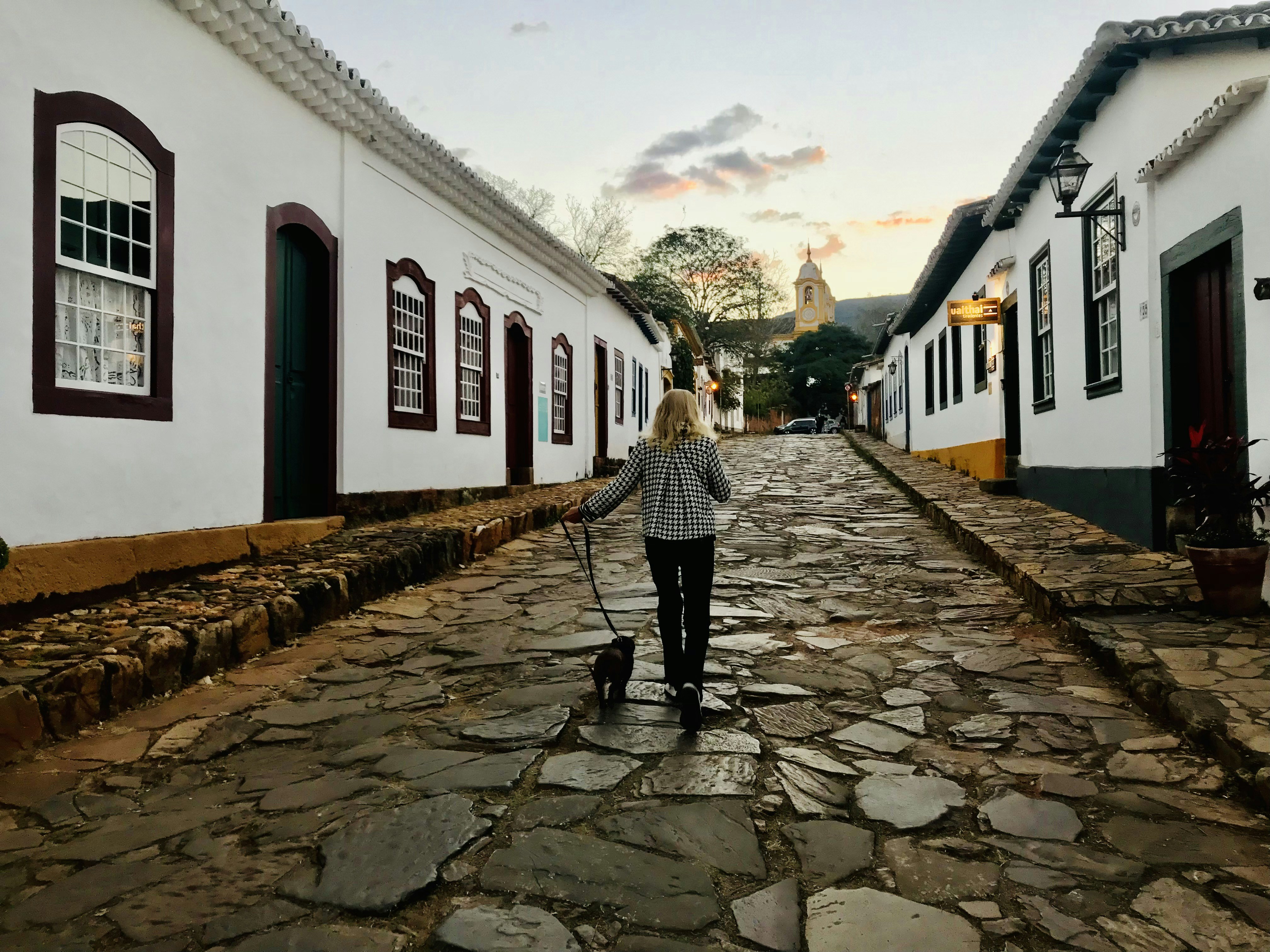 woman in black and white striped long sleeve shirt walking on gray concrete pathway