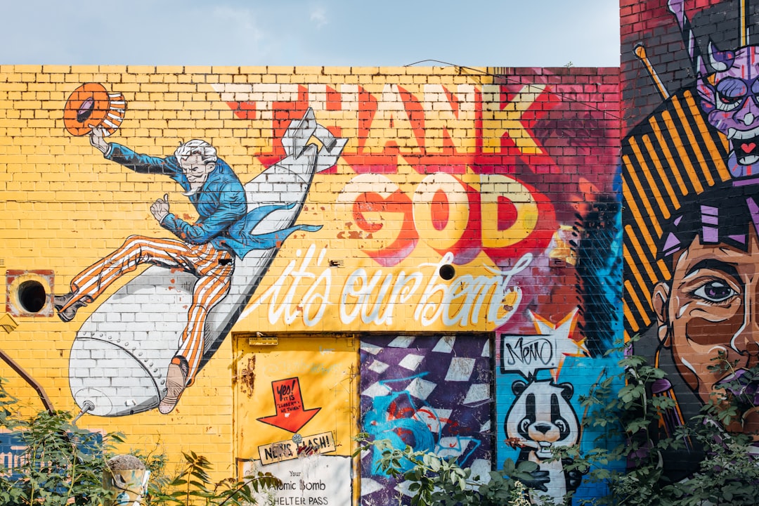 man in blue shirt and brown pants standing on wall with graffiti