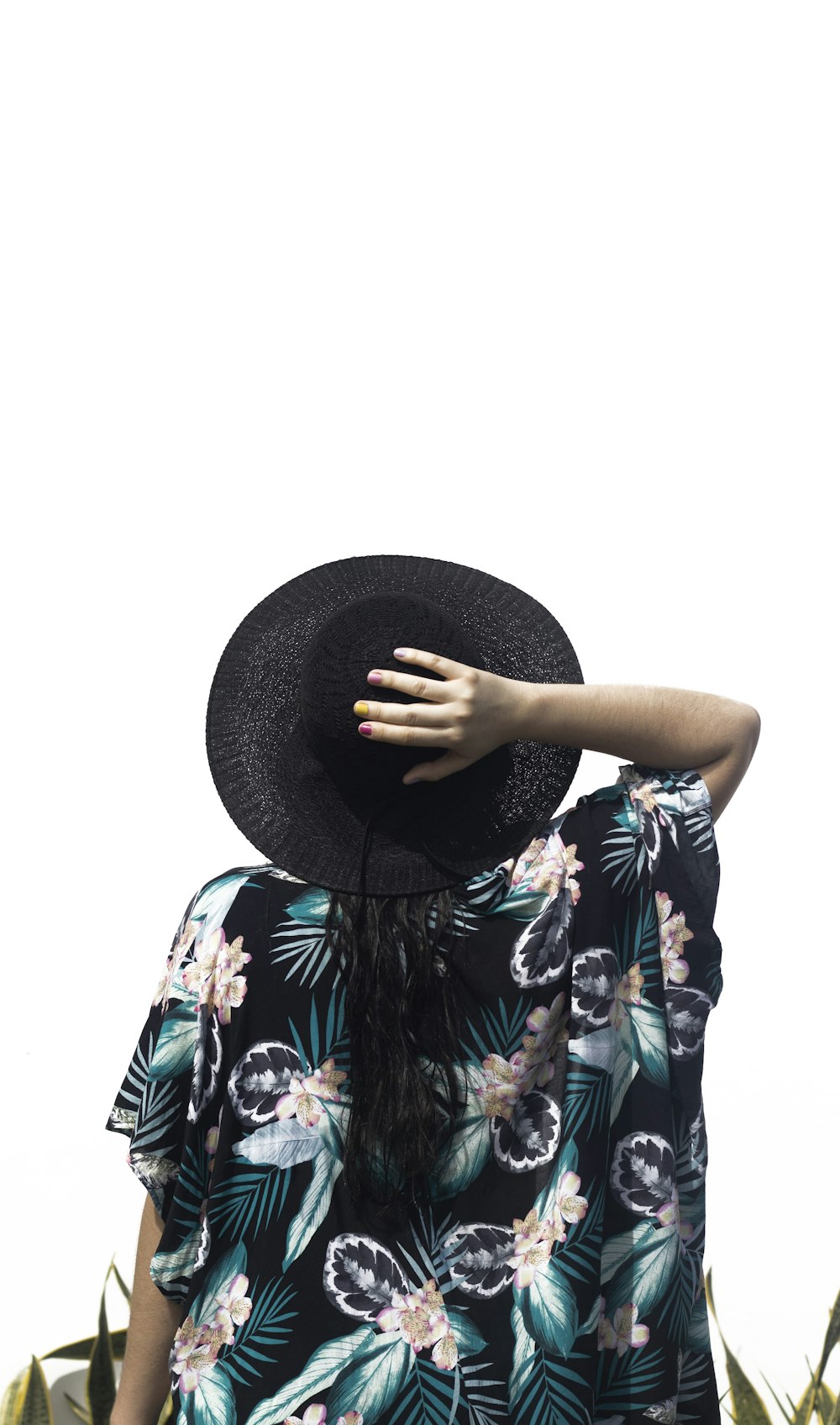 woman in blue white and green floral dress holding black fedora hat