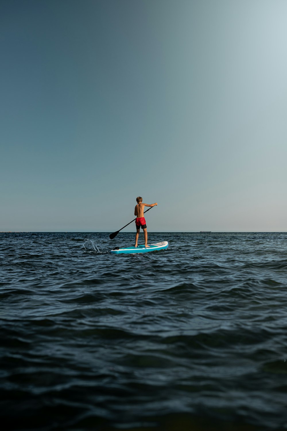 woman in blue and white surfing board on sea during daytime