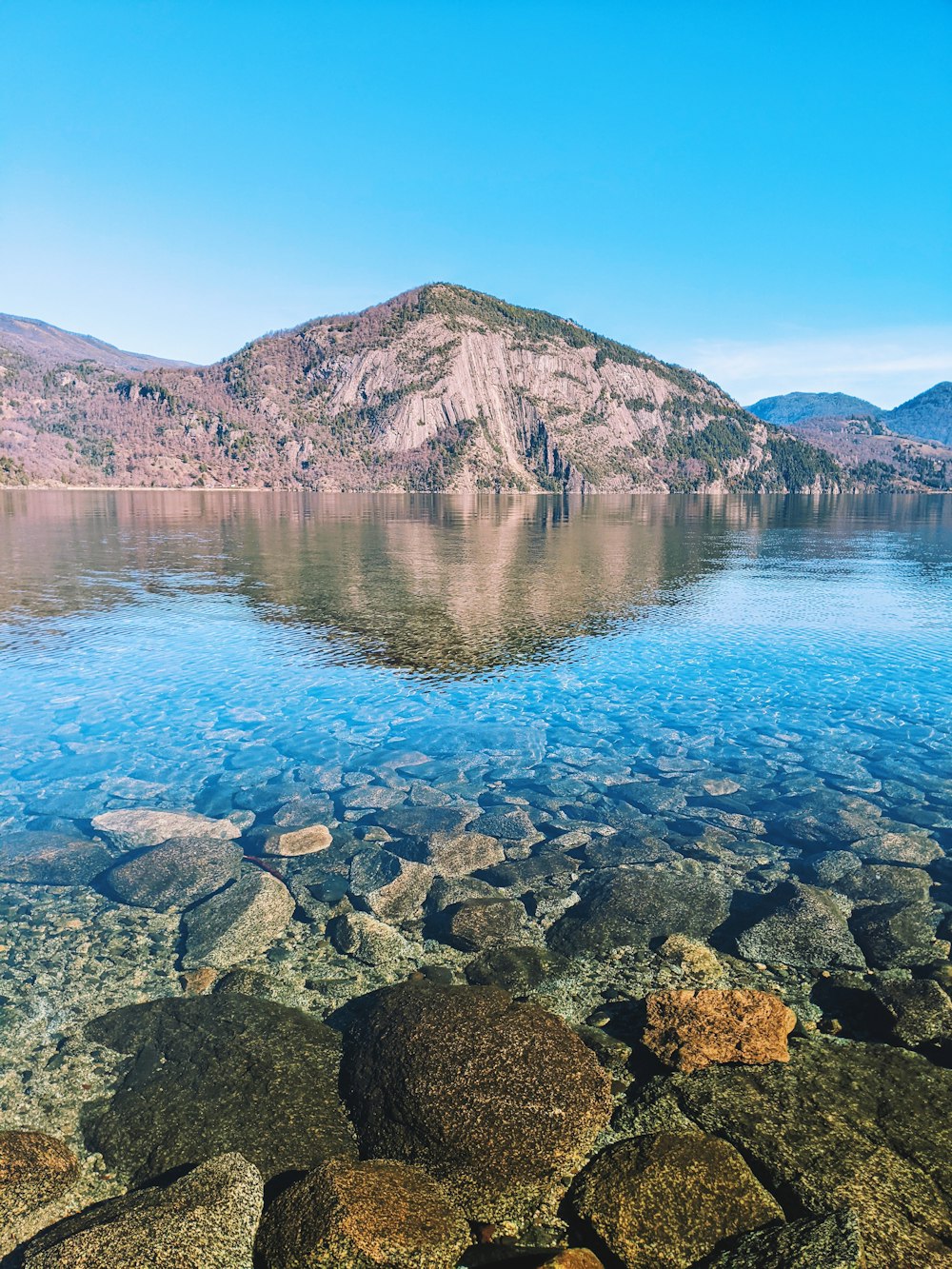 brown rocky mountain beside body of water during daytime