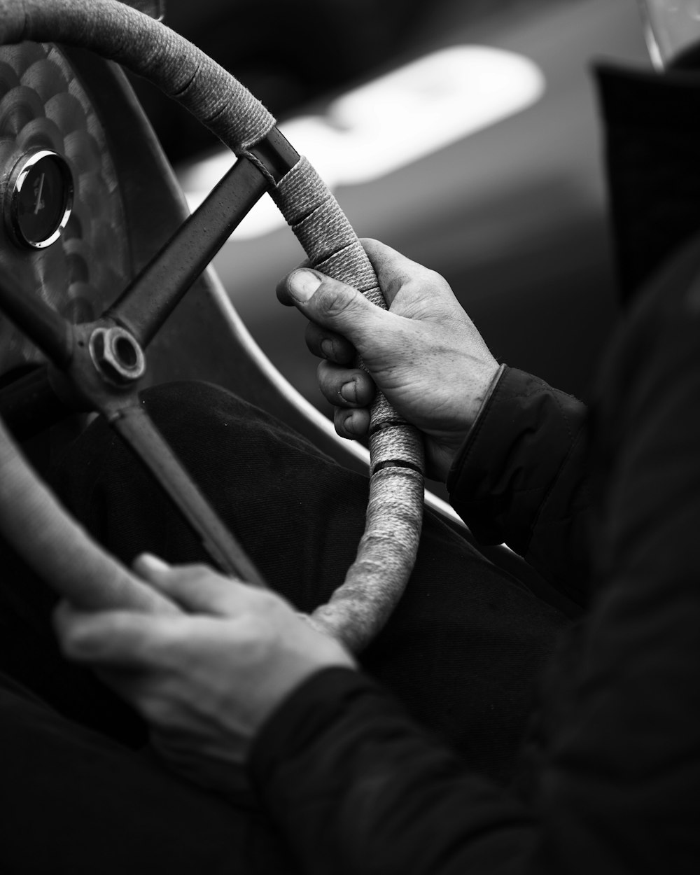 grayscale photo of man in long sleeve shirt holding steering wheel