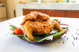 Close-up of crispy golden fried ayam pop served with sambal and fresh lime on a rustic plate