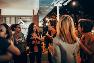 woman in black and white floral shirt standing near people during nighttime