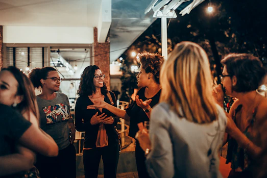 woman in black and white floral shirt standing near people during nighttime