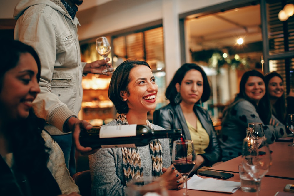 woman in gray cardigan holding glass cup