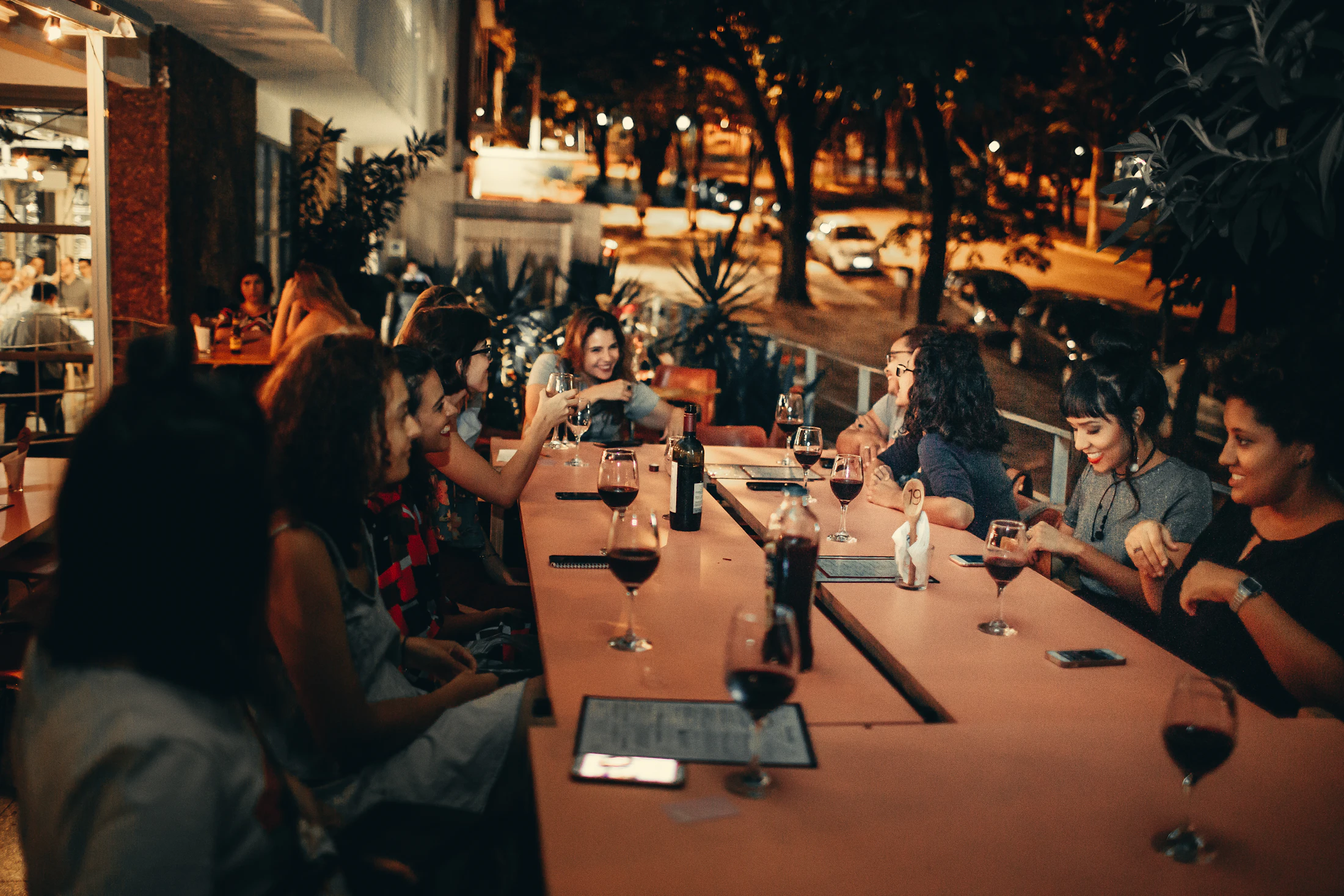 A long dinner table under the trees and string lights