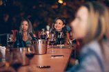Guests enjoying a lively wine tasting event around a rustic wooden table.