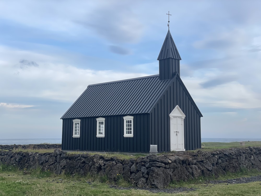 Schwarz-weiße Holzkirche auf grünem Grasfeld unter weißen Wolken und blauem Himmel während