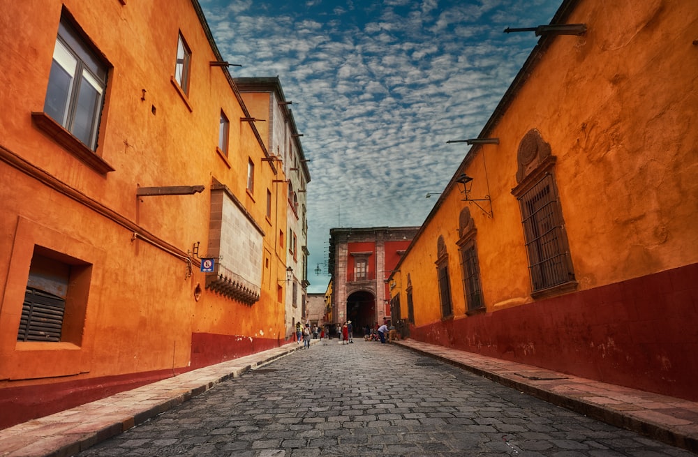 people walking on street between buildings under blue sky during daytime