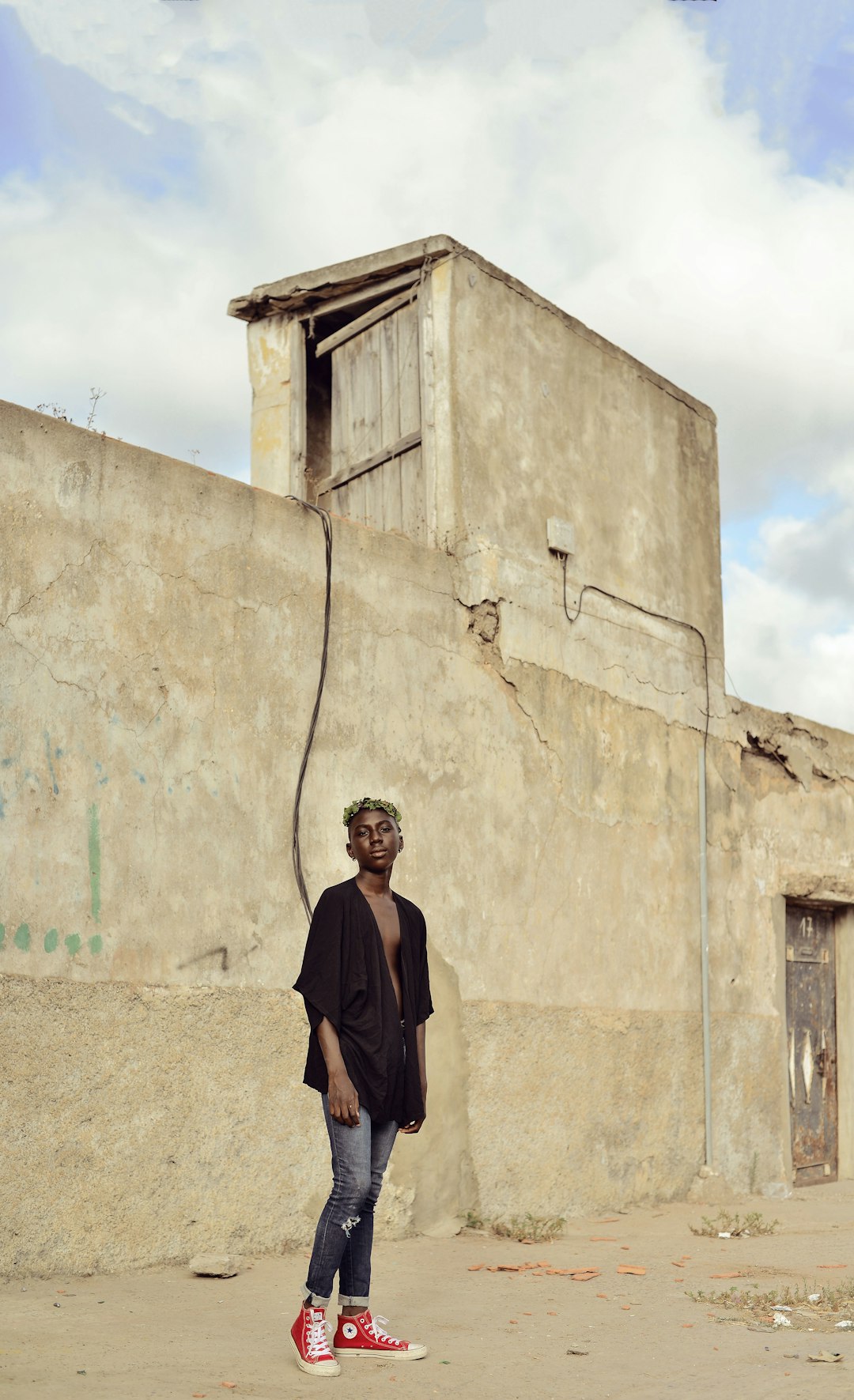 man in black coat standing beside beige concrete wall during daytime