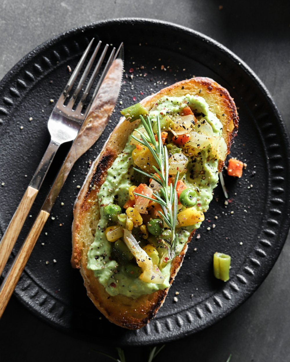 brown and green dish on black plate, avocado breakfast pizza