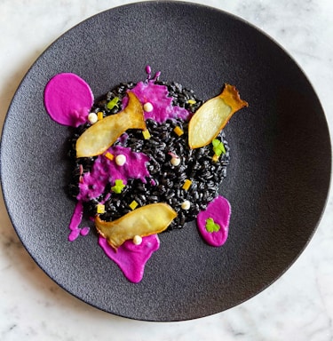 A vibrant plate of black rice with seafood, garnished with fresh herbs.
