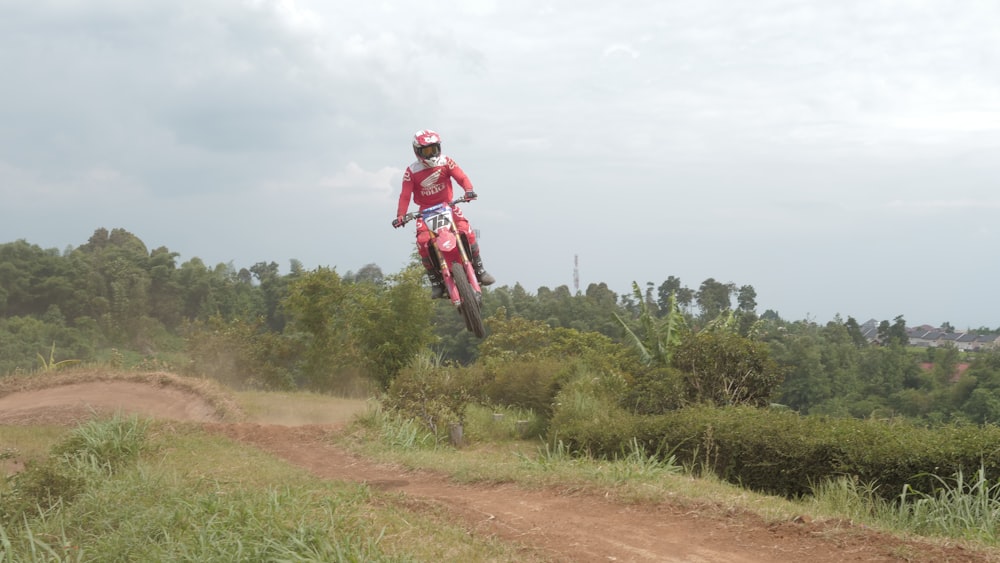 man in red jacket riding motocross dirt bike on dirt road during daytime